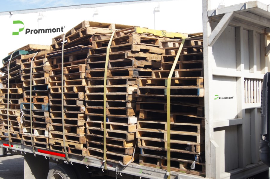 Transporte de carga de pallets de madera usados Fotografía de pilas altas de pallets de madera usados asegurados con correas amarillas sobre la plataforma de un camión.