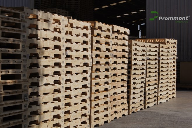 Almacenamiento de pallets de madera nuevos apilados. Imagen de columnas de pallets de madera limpia y nueva apilados ordenadamente en filas colocadas fuera de un almacén.