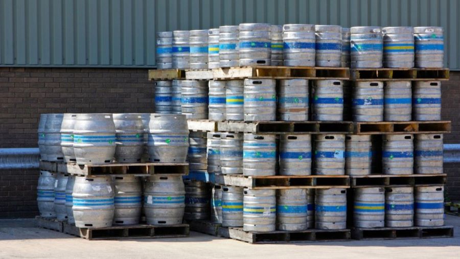 Carga de la industria cervecera protegida para su transporte. imagen de un lote de tarimas con carga de barriles de la industria cervecera al exterior de un almacén