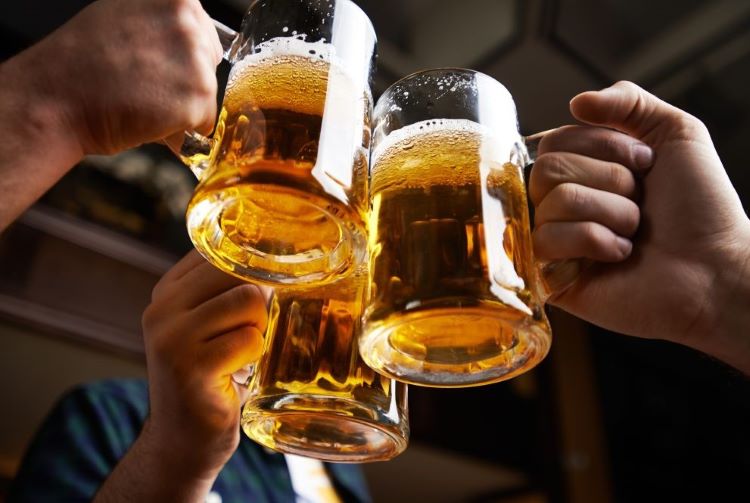 Tarros de cerveza fría que ha sido transportada en tarimas de de madera Imagen de tres personas brindado con una tarro de cerveza que se transportó en tarimas de madera desde la planta hasta un restaurante.