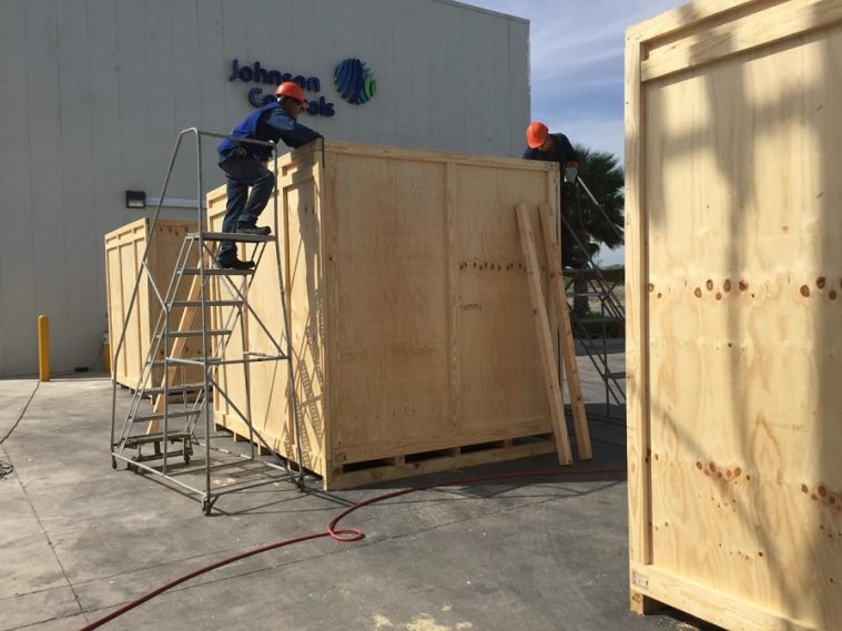 Dos trabajadores en escaleras construyendo una estructura de madera en un sitio industrial.