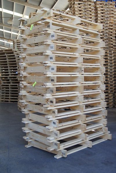 Tarima de madera de calidad, solo en Prommont Tarima de madera: Imagen de una pila de tarimas de madera de pino claro, dentro de un almacén.