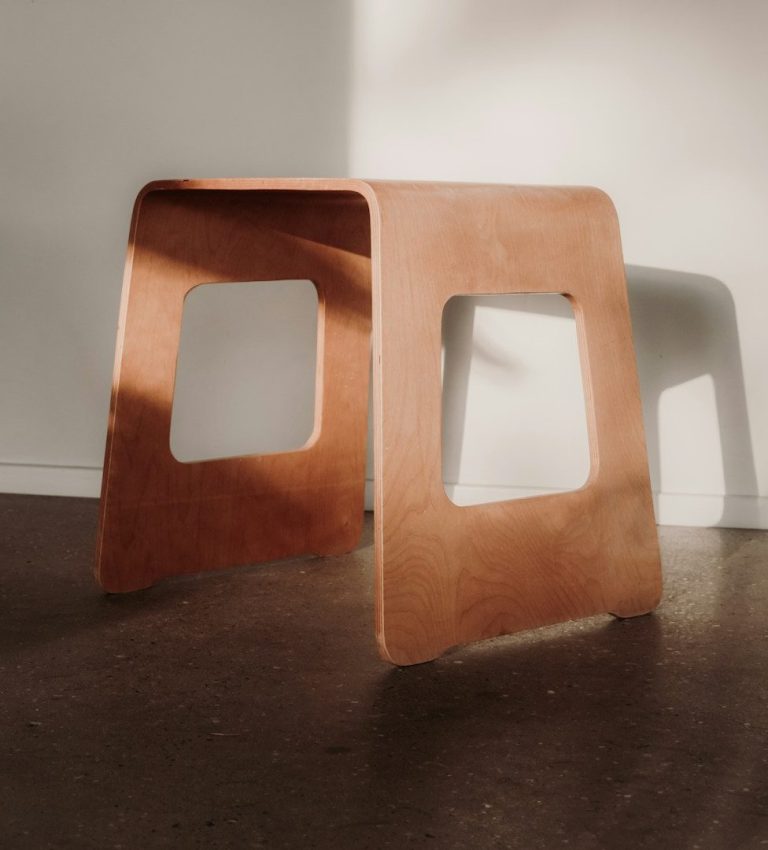 Taburete moderno de madera con un diseño minimalista y aberturas en los laterales.
