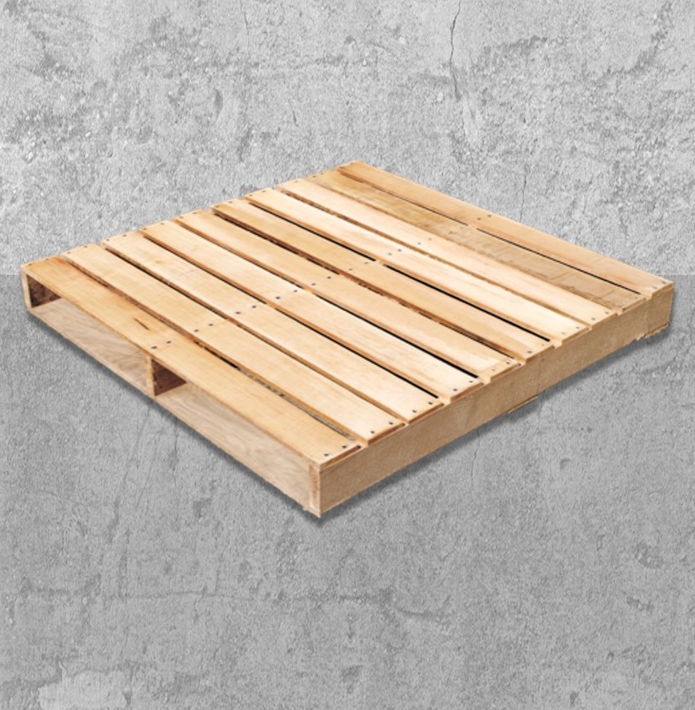 Venta de tarimas de madera con cargador de tablón. Venta de tarimas de madera clara, de tipo larguero o con cargador de tablón, mostrada en un ángulo sobre un piso de cemento gris.