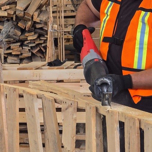 Operario- desarmando- tarimas-madera para-regeneración Toma fotográfica de operario procesando tarimas de madera recicladas para su inspección a detalle